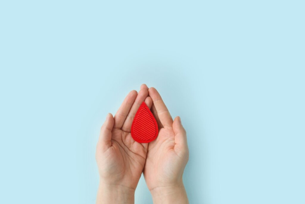 Mãos de uma pessoa segurando um objeto vermelho em forma de gota, com textura de linhas em relevo