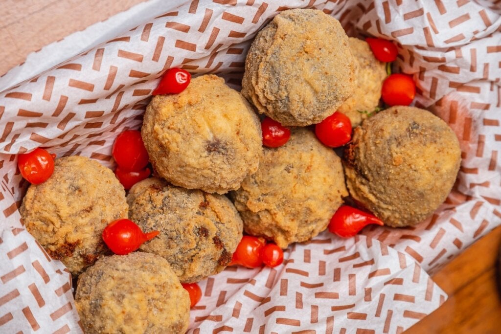 Bolinhos de feijão-preto com couve em um recipiente branco com papel branco com desenhos de folhas vermelhas 