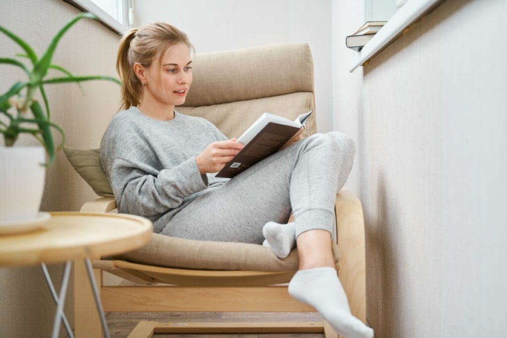 mulher sentada em uma poltrona e lendo livro