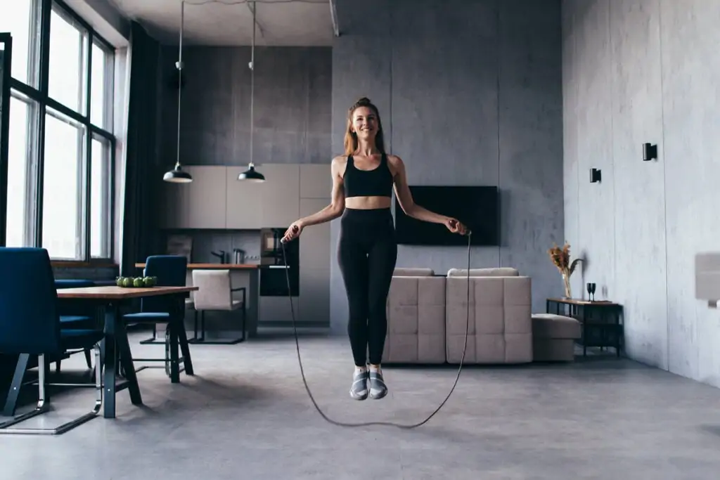 Mulher em uma sala de estar pulando corda 