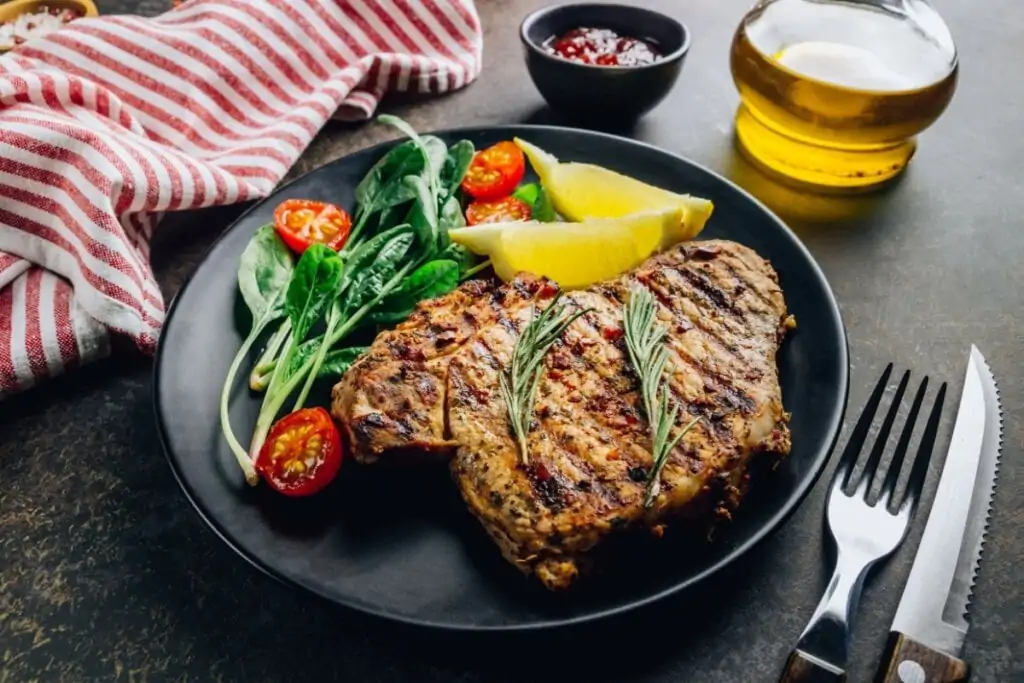 Bisteca grelhada servida com salada em prato de cerâmica preto