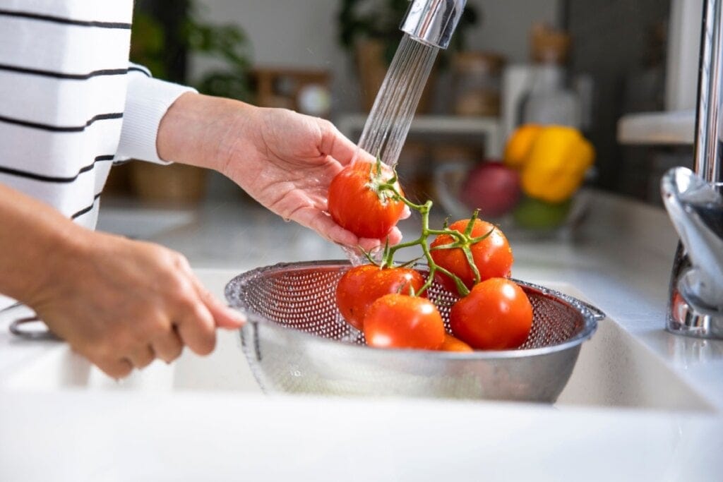 Mãos de uma mulher lavando tomates