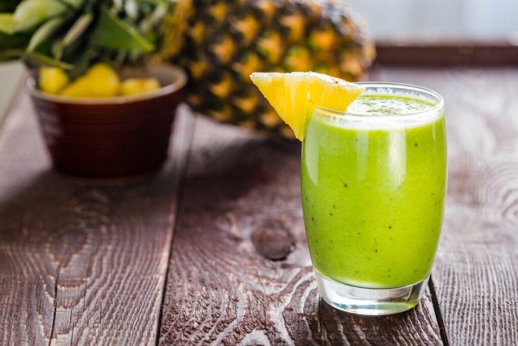 Copo de vidro com suco verde decorado com uma rodela de abacaxi