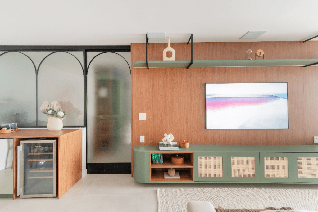 Sala decorada com móveis em madeira e o móvel abaixo da TV é  verde com palhinha 