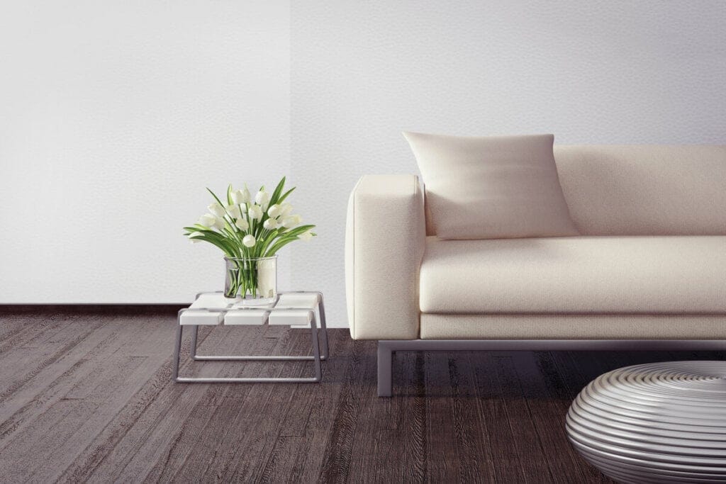 Mesa quadrada com um vaso de planta e sofá branco ao lado