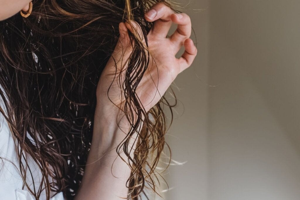 Mulher segurando uma mecha de cabelo molhado nas mãos
