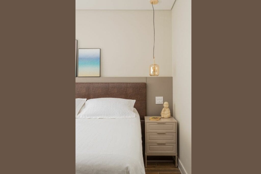 Cabeceira de couro marrom atrás de uma cama com lençol branco