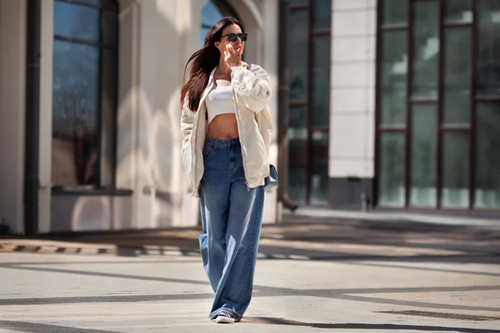 Mulher usando calça jeans larga e blusa branca andando pela rua