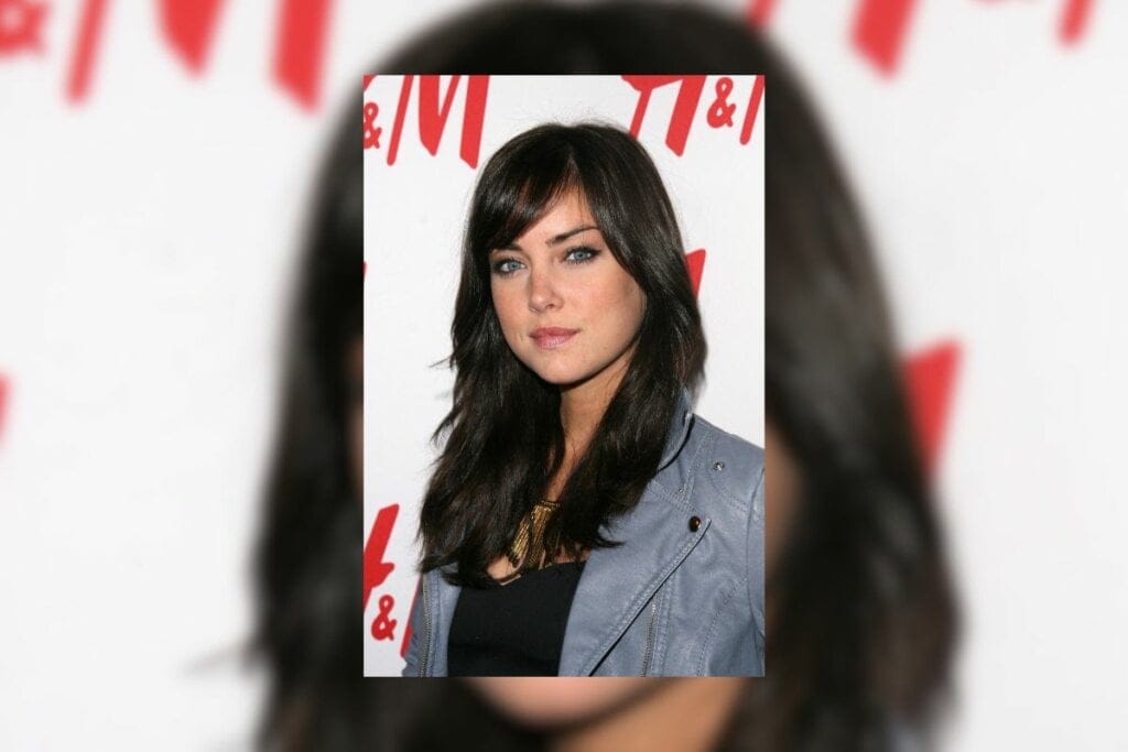 Mulher com cabelo longo e preto com franja diagonal posando para foto