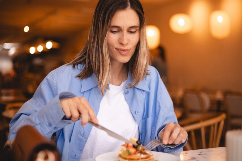 Mulher sentada em um restaurante comendo