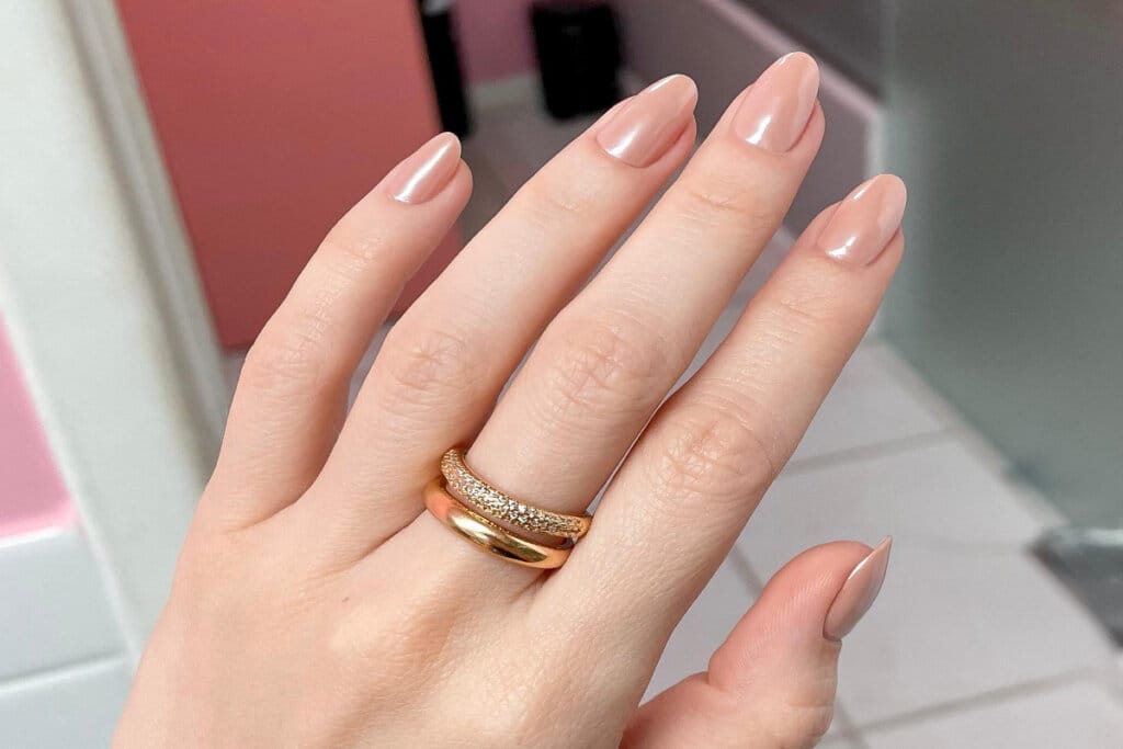 mão com unhas em tom de nude cintilante