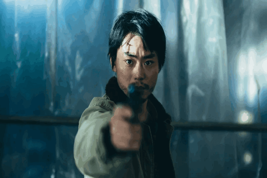 Homem oriental com um ferimento na testa e segurando uma arma, usando casaco verde 