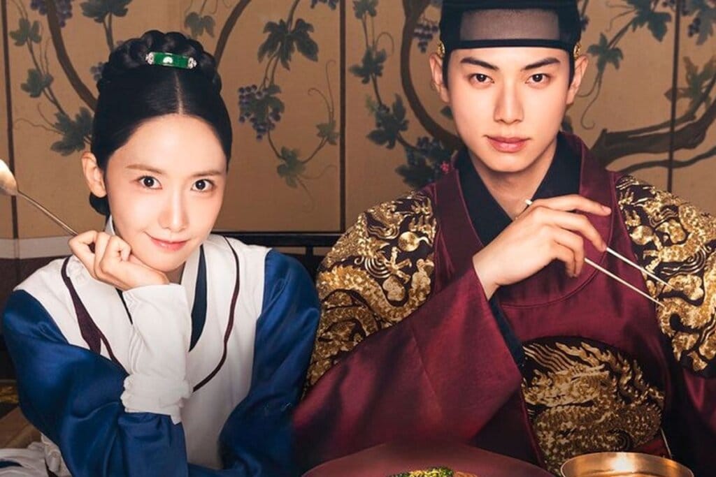 Protagonistas da série "Bon Appétit Vossa Majestade" sentados e olhando para frente 
