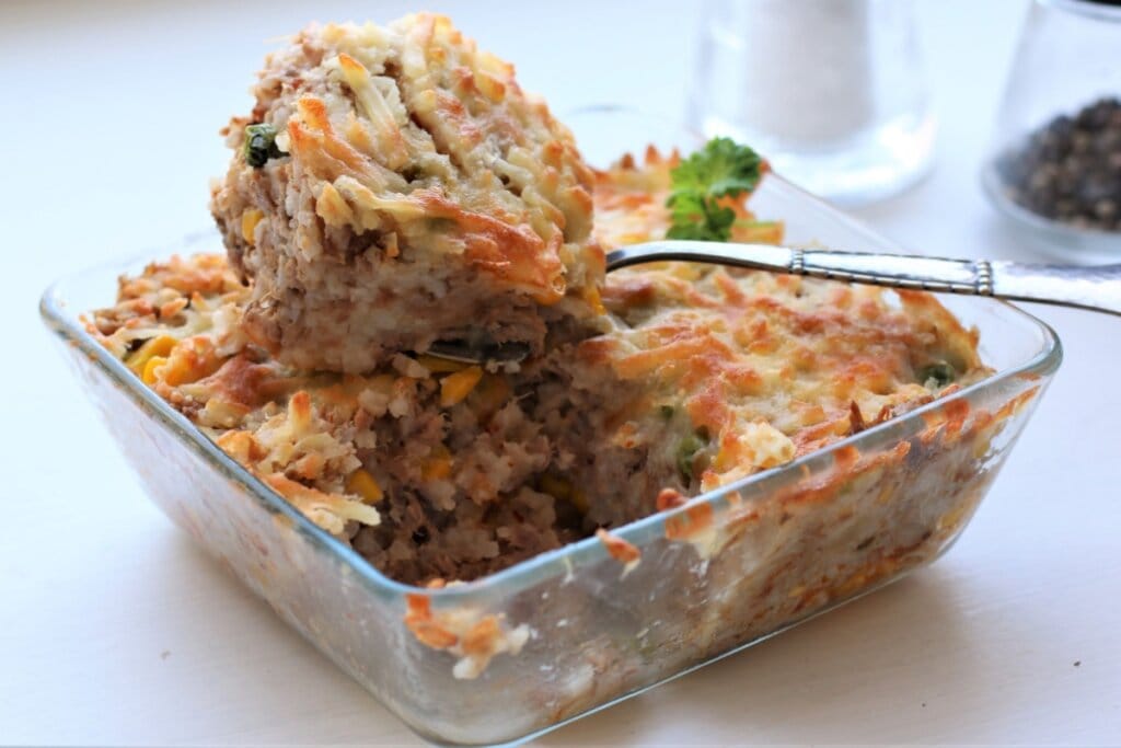 Arroz de forno com atum servido em tigela de vidro em cima de mesa branca de madeira