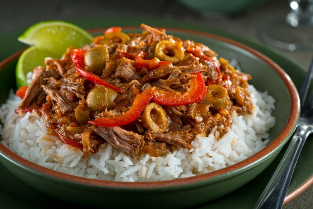 Ropa vieja cubana de fraldinha em cima de arroz em prato esverdeado