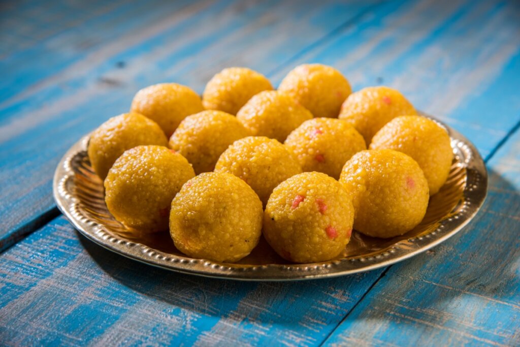 Bolinhos de cuscuz com calabresa em um prato de metal sobre uma mesa de madeira azul 