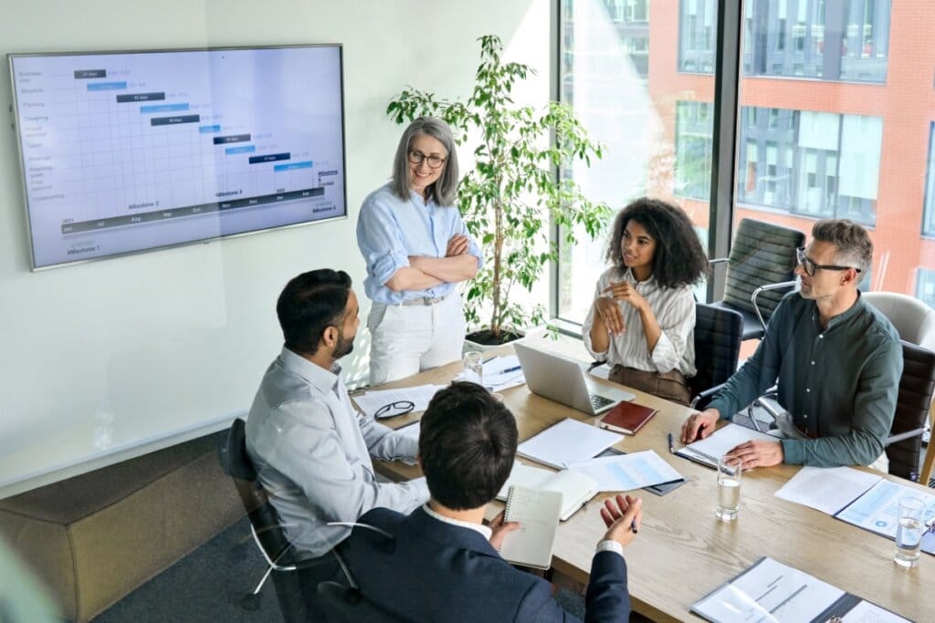 Pessoas em uma sala de reunião com uma tela com gráfico atrás