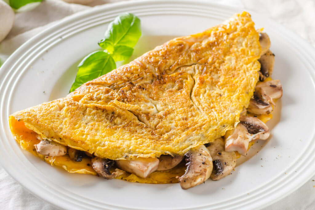 Omelete recheado com cogumelos em cima de um prato branco 