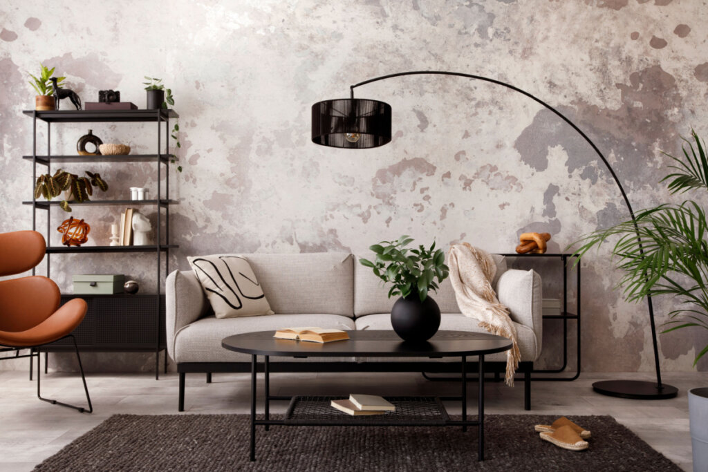 Interior de uma sala de estar com sofá, poltrona, mesa de centro preta, abajur e elegantes acessórios pessoais