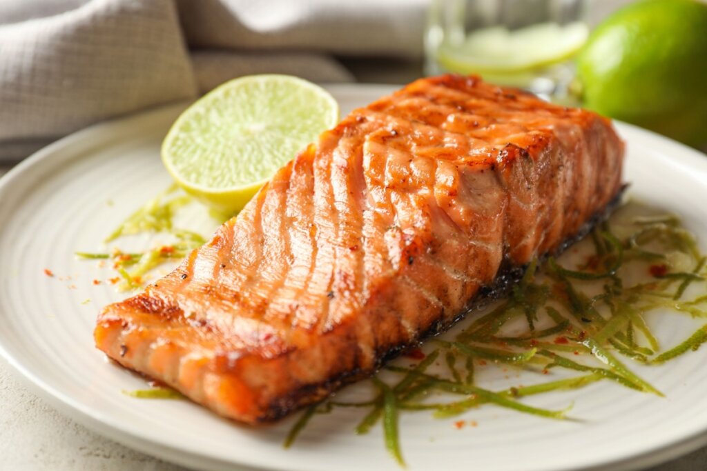 Salmão grelhado em prato estampado com metade de limão ao lado