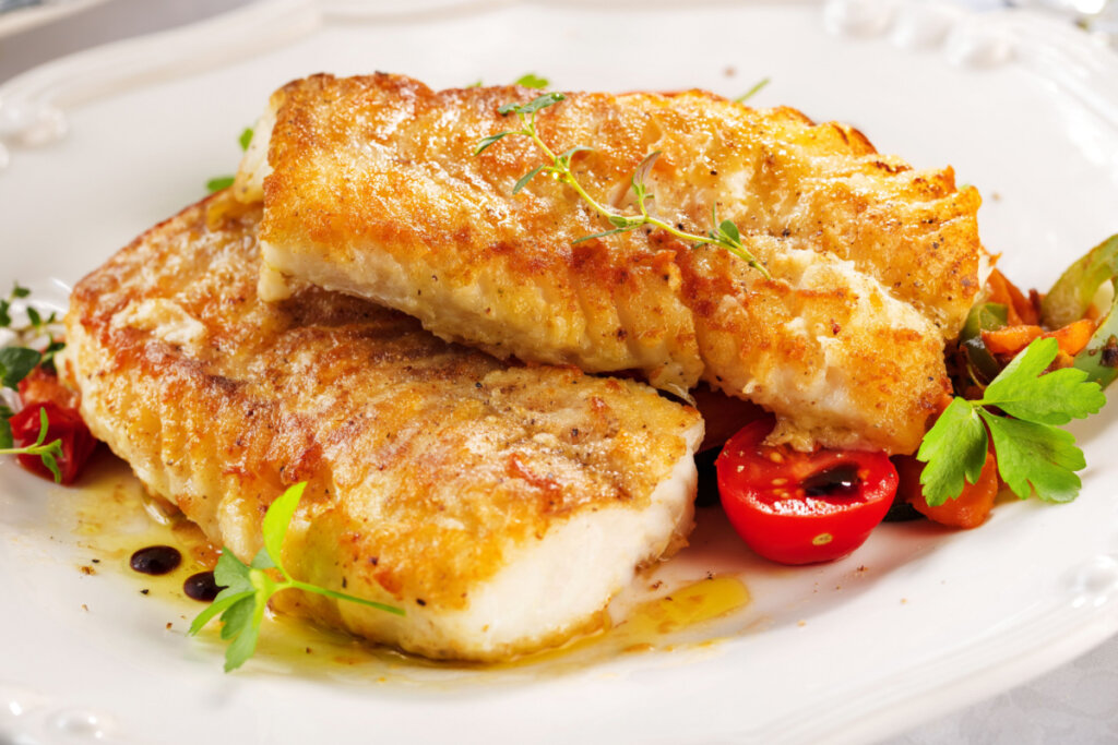 Tilápia assada servida com tomates-cerejas e cenoura, regada no azeite.