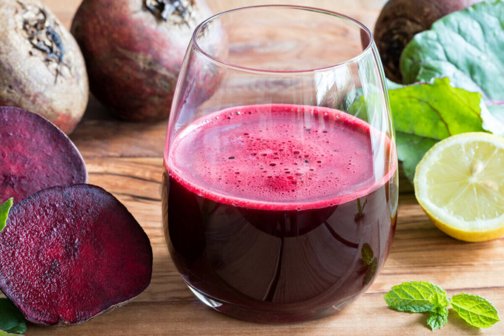 Suco de beterraba em um copo de vidro em cima de uma mesa de madeira