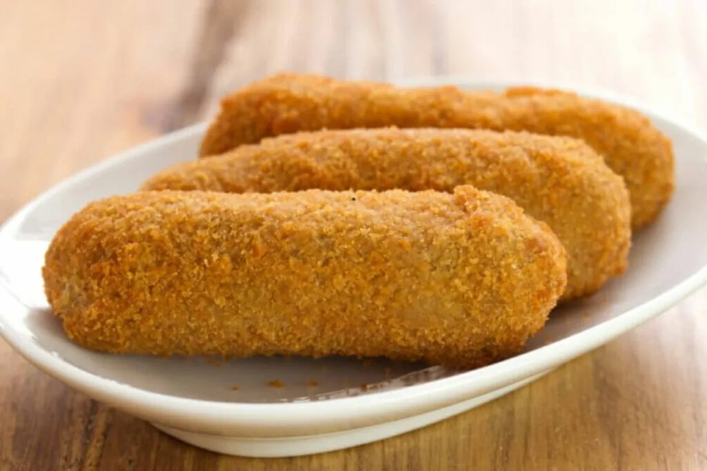 Três croquetes em um prato branco 