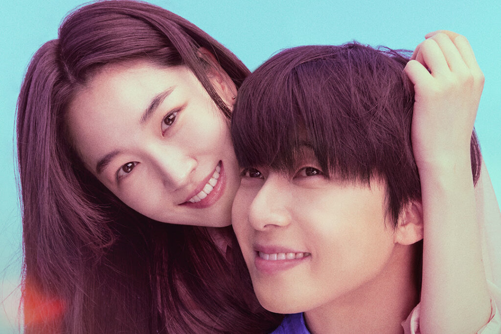 mulher de cabelo comprido sorrindo e com os braços em volta de cabeça de homem, que tem cabelo curto e está sorrindo