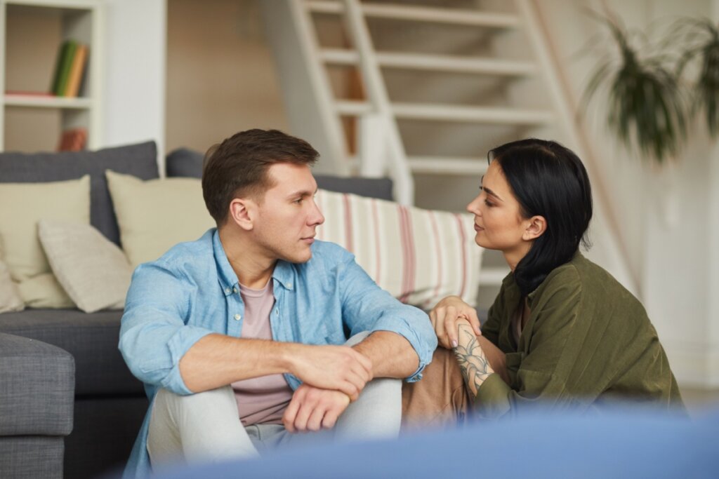 Homem e mulher sentados perto de um sofá, conversando