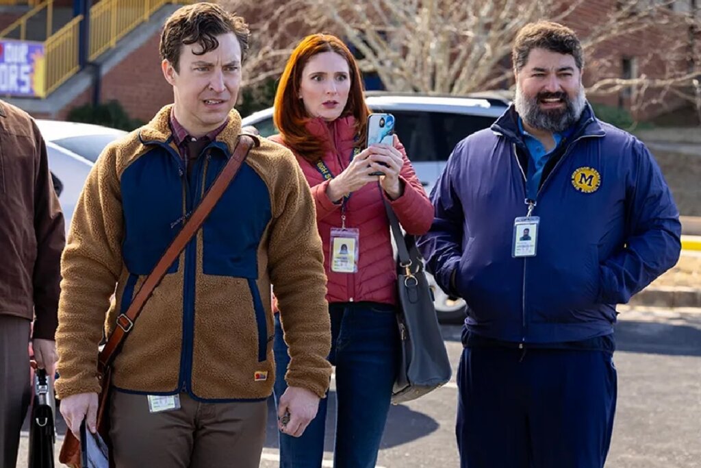 Três adultos em ambiente externo escolar observando algo à frente