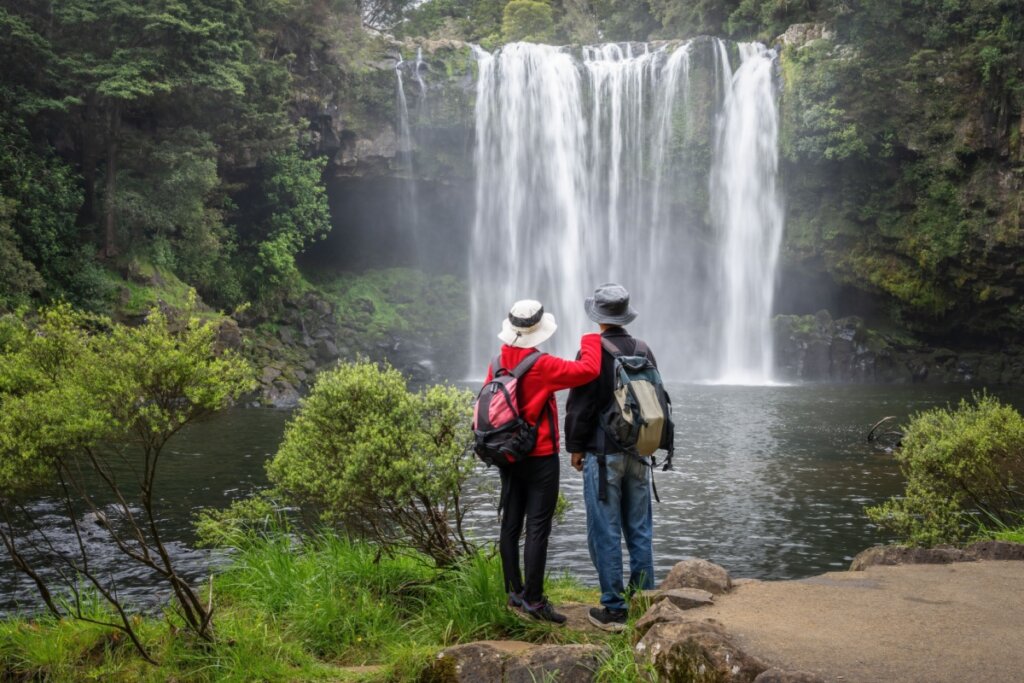 Casal apreciando a vista de Rainbow Falls no rio Kerikeri. Northland. Nova Zelândia