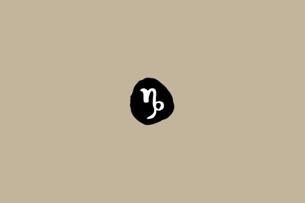 Símbolo do signo de Capricórnio em branco dentro de um círculo preto sobre um fundo bege