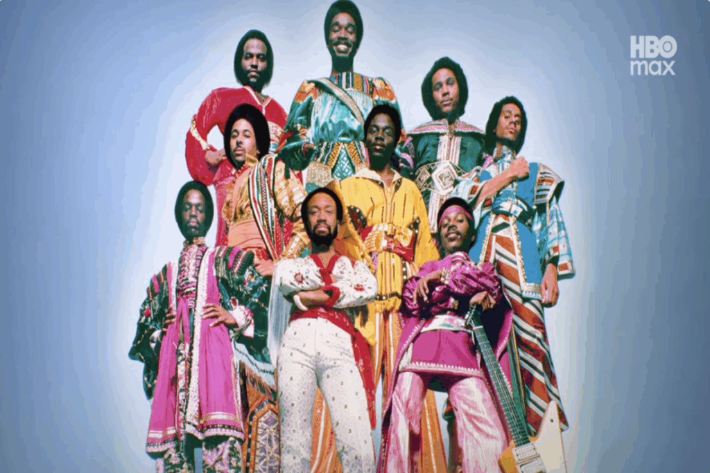 Grupo de homens usando roupas coloridas um ao lado do outro em fundo azul claro