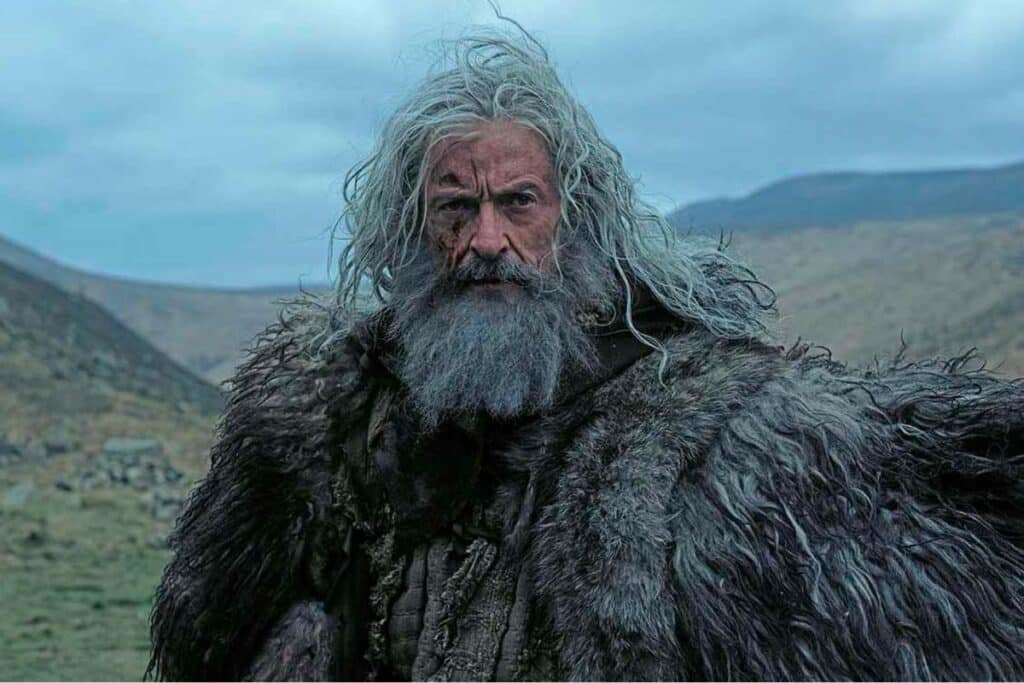 Robin Hood, com barba e cabelo longo branco, andando em montanhas