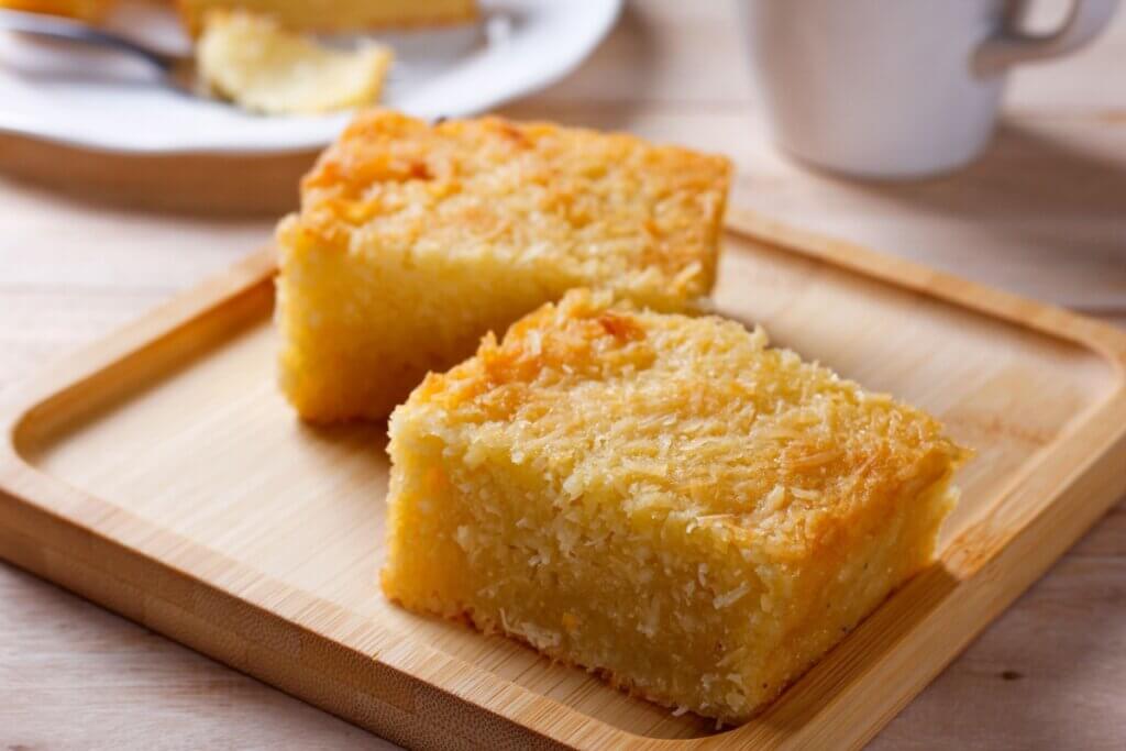 Dois pedaços de bolo de mandioca em tábua de madeira