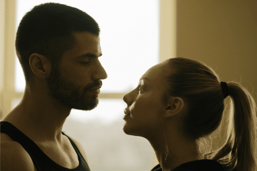 mulher de homem de perfil, um de frente para o outro. ele tem cabelo curto e barba. ela tem cabelo loiro e preso em rabo de cavalo