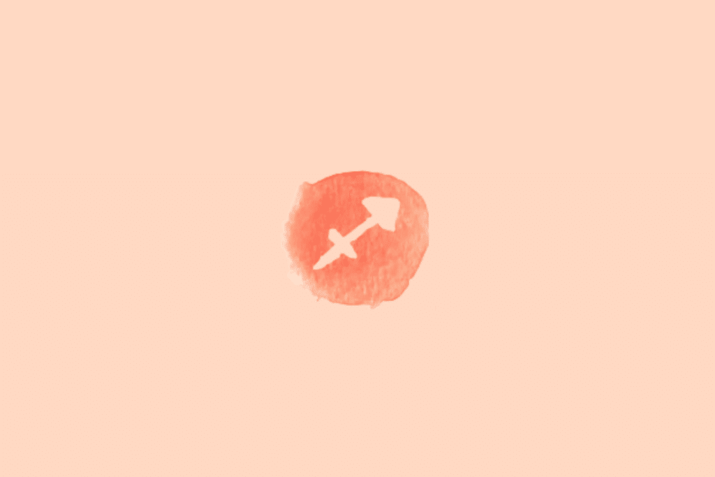 Ilustração do signo de Sagitário sobre fundo uniforme em tom pêssego-claro. No centro, há um círculo irregular em vermelho-alaranjado, com textura de aquarela e bordas desiguais. Dentro dele, o símbolo de Sagitário aparece em tom creme, representado por uma flecha diagonal que aponta para o alto à direita. Um segundo traço diagonal cruza a linha principal, formando uma figura semelhante a uma seta estilizada.
